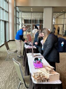 Reuleaux cars on a long table. A conference-goer looks at a book on the table.