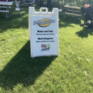A signboard reading "DNR Activities. Make and Take Pinwheel and color sheets. MathHappens Math activities for all ages"