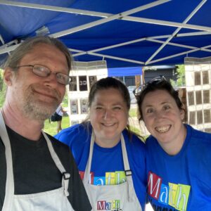 Three MathHappens facilitators take a selfie beneath a canopy.