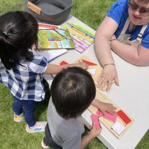 two young children and a MathHappens facilitaor are at a low table with chunky shape puzzles made for tiny hands
