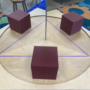 Three cubes—two are reflections in a mirror book.